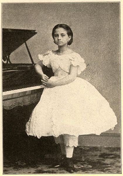 Young woman stands next to piano