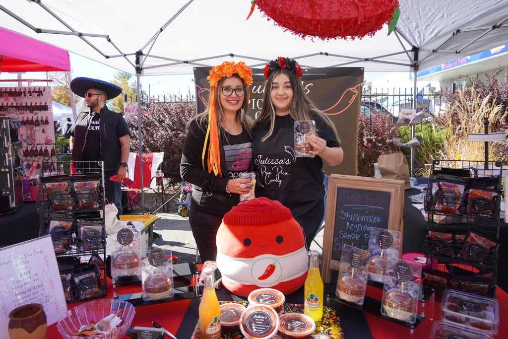 Two women are pictured holding spicy candy at a vendor stall