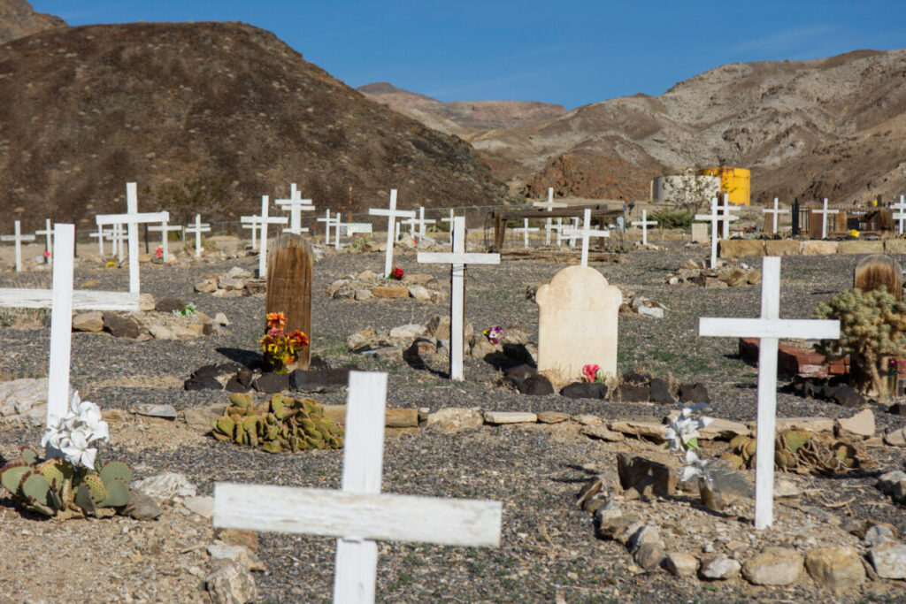 Headstones in a cemetery are pictured set against the mountains