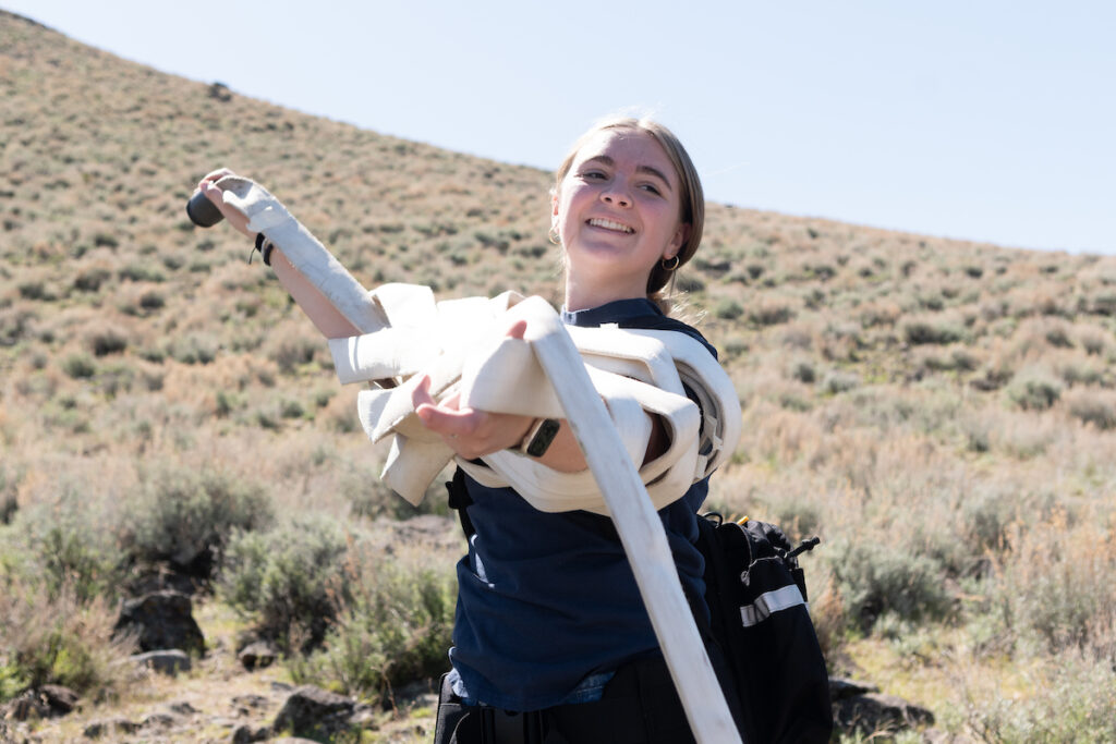 A smiling young woman is pictured holding a tangle of a fire hose