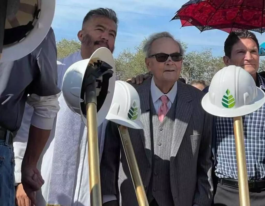 three men stand with shovels before them