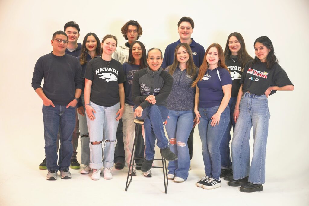 12 people standing together posing in front of white screen