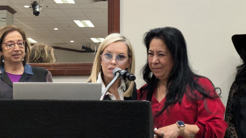 women at podium speak into microphone