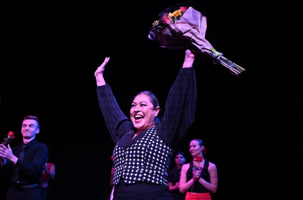 woman with raised hands and flowers in her left hand