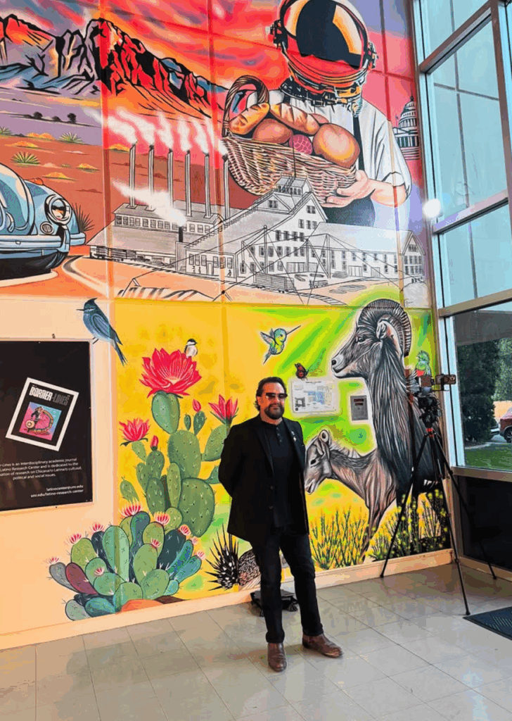 Man stands in building hallway in front of mural