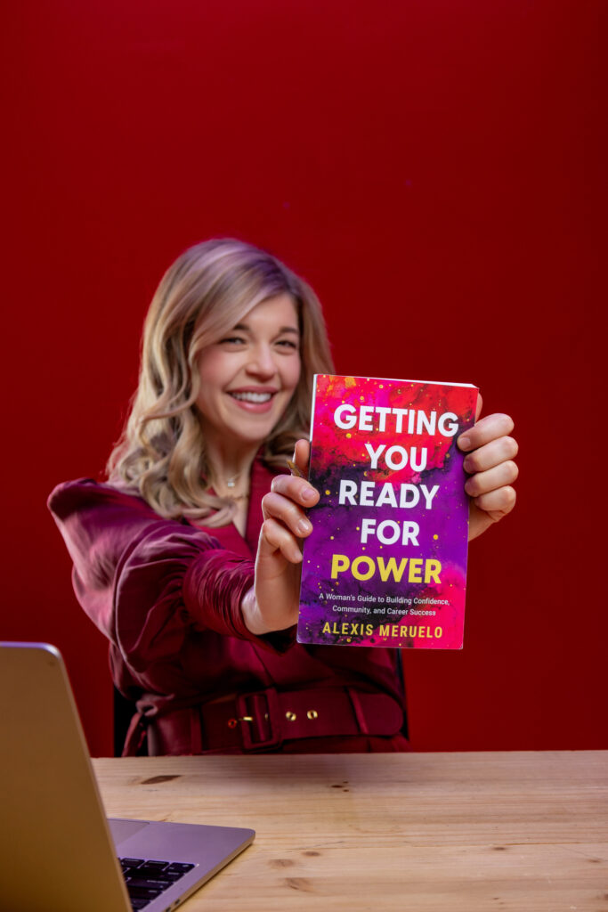 blond woman seated in red at desk holding book that says, "Getting You Ready for Power"