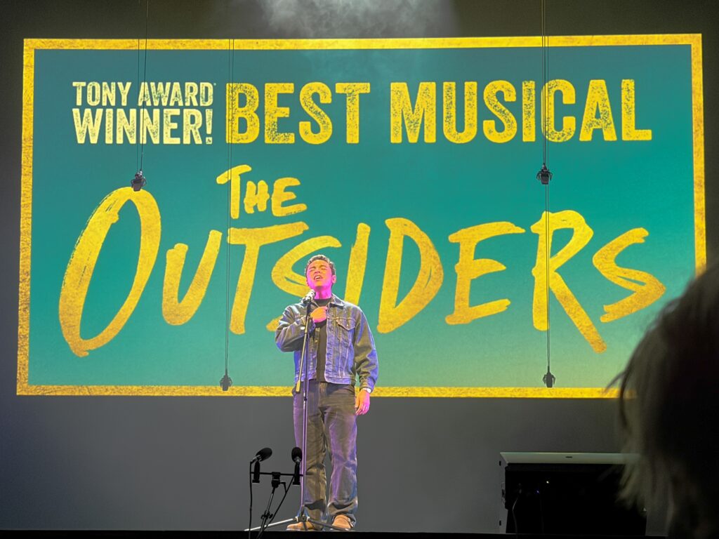 man on stage sings into microphone