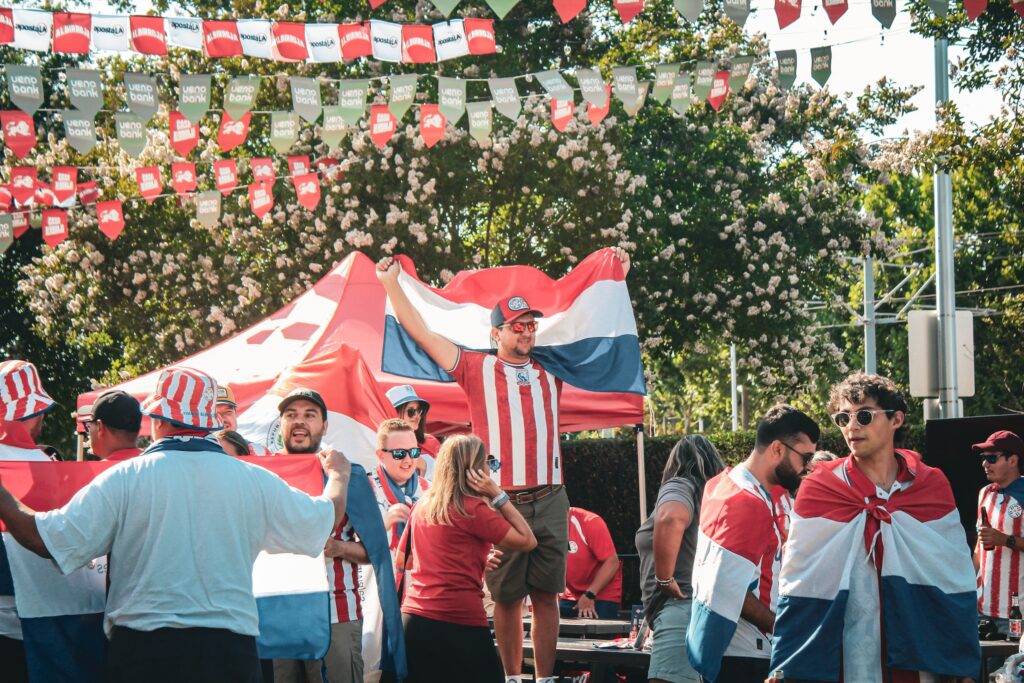 man holds up flag from Paraguay in the crowd