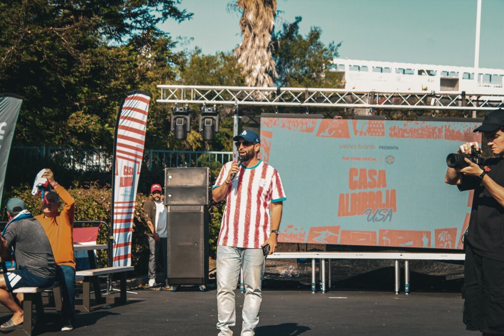 man with microphone speaks to crowd from stage