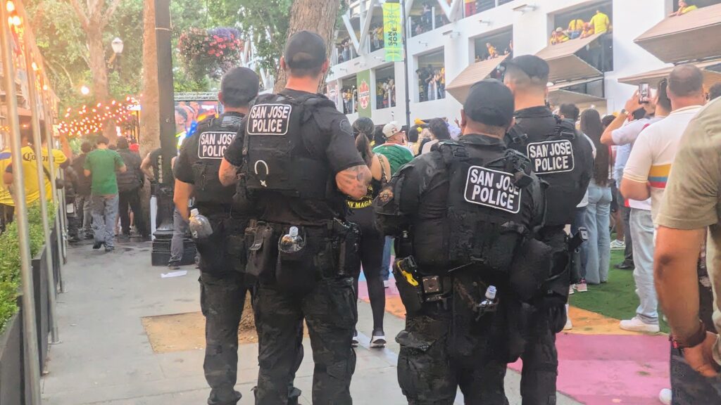 four san josé police officers look over a crowd