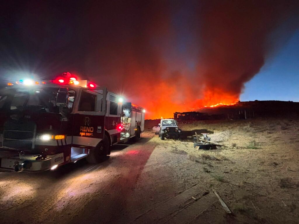 Fire trucks stationed with fire burning behind them