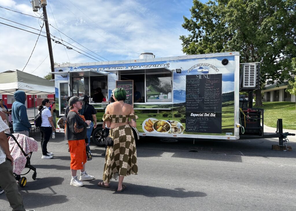 A crowd of people form in front of food truck