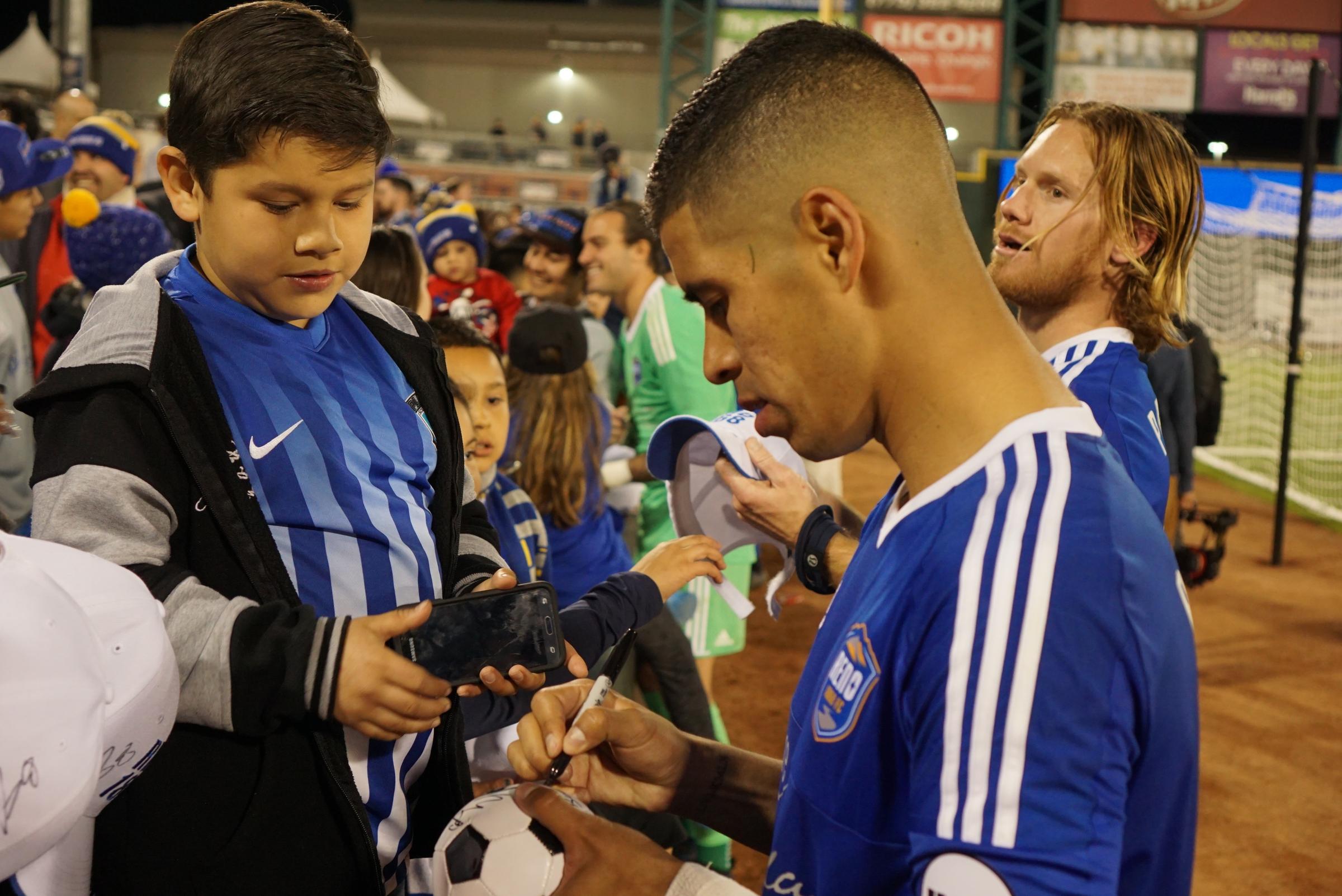 Junior Burgos signs autographs at the end of the game. Fans are willing to get anything signed from Burgos, including T-shirts and mini soccer balls.
