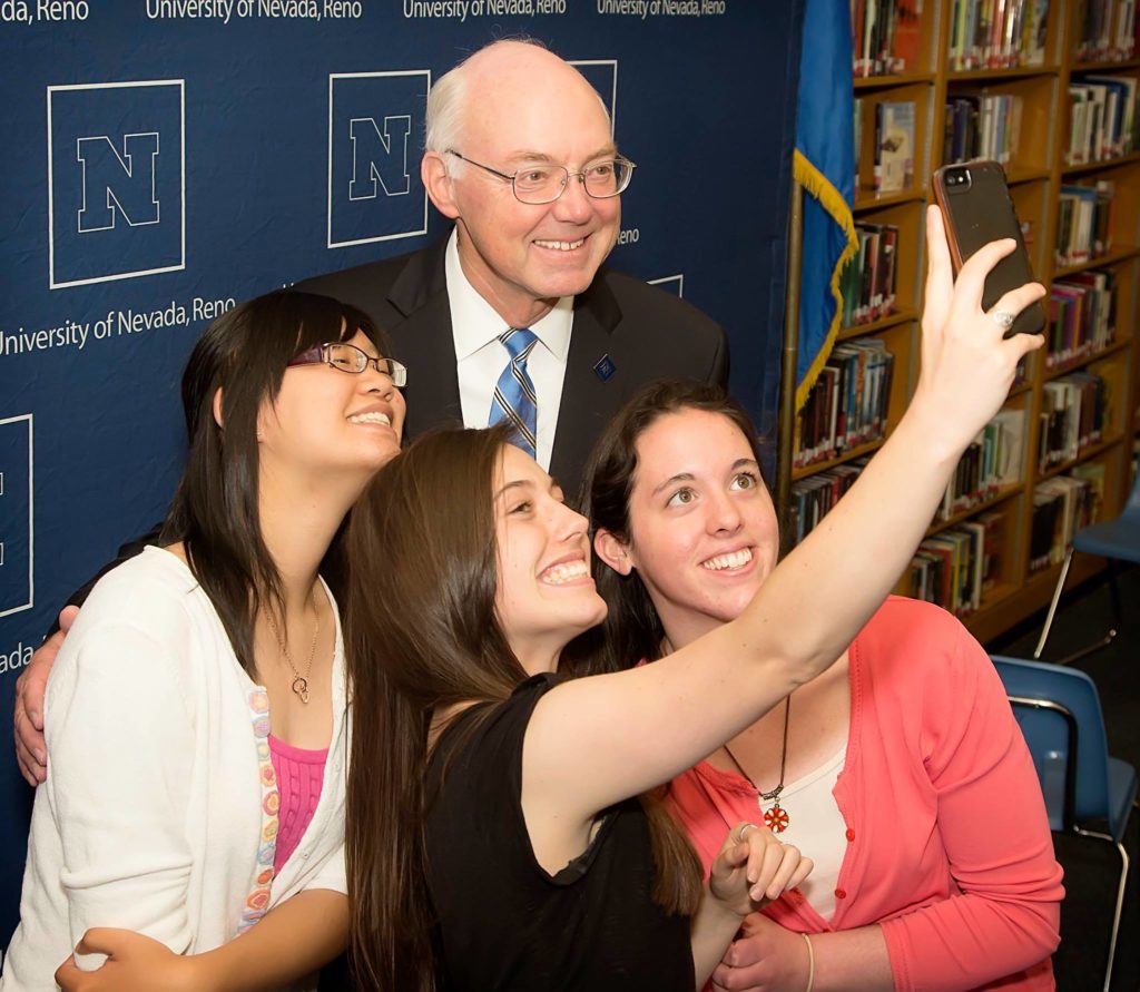 UNR's President, Marc Johnson, taking a selfie three UNR students.