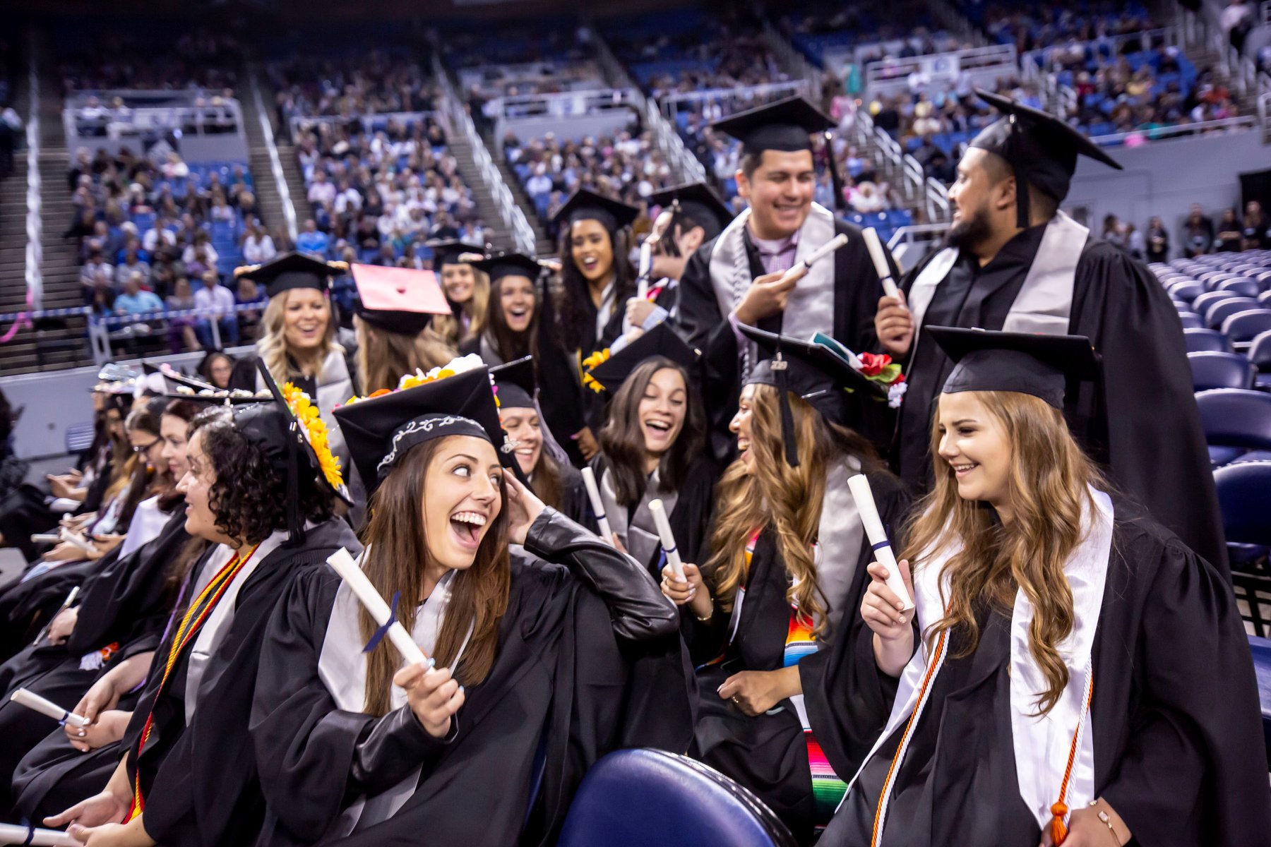 Recent graduates from the University of Nevada-Reno, smiling at one another after receiving diplomas.