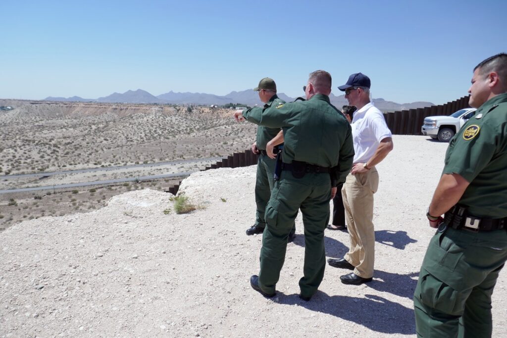 Border Patrol agents alongside the border wall.