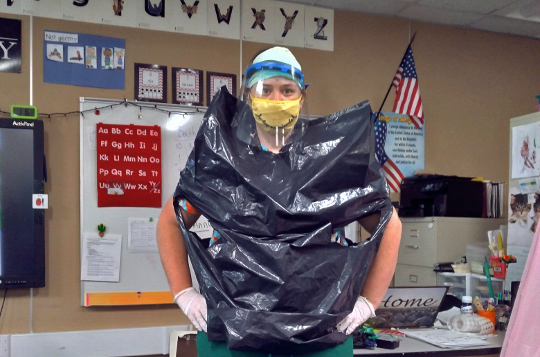 Teacher covered in black trash bag that serves as a gown and protection against COVID-19