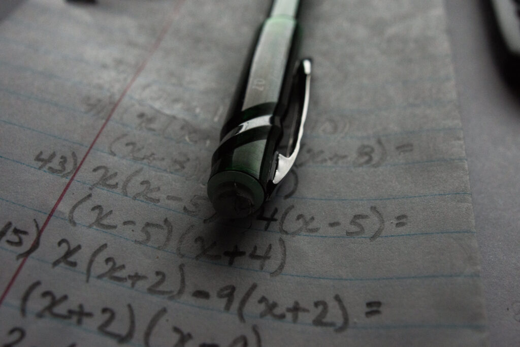Math formulas written on lined paper with a pen resting on top. Unlike the math homework pictured above, Piceno says that due to COVID-19, he converted all his coursework to digital assignment to avoid passing papers back and forth with students.