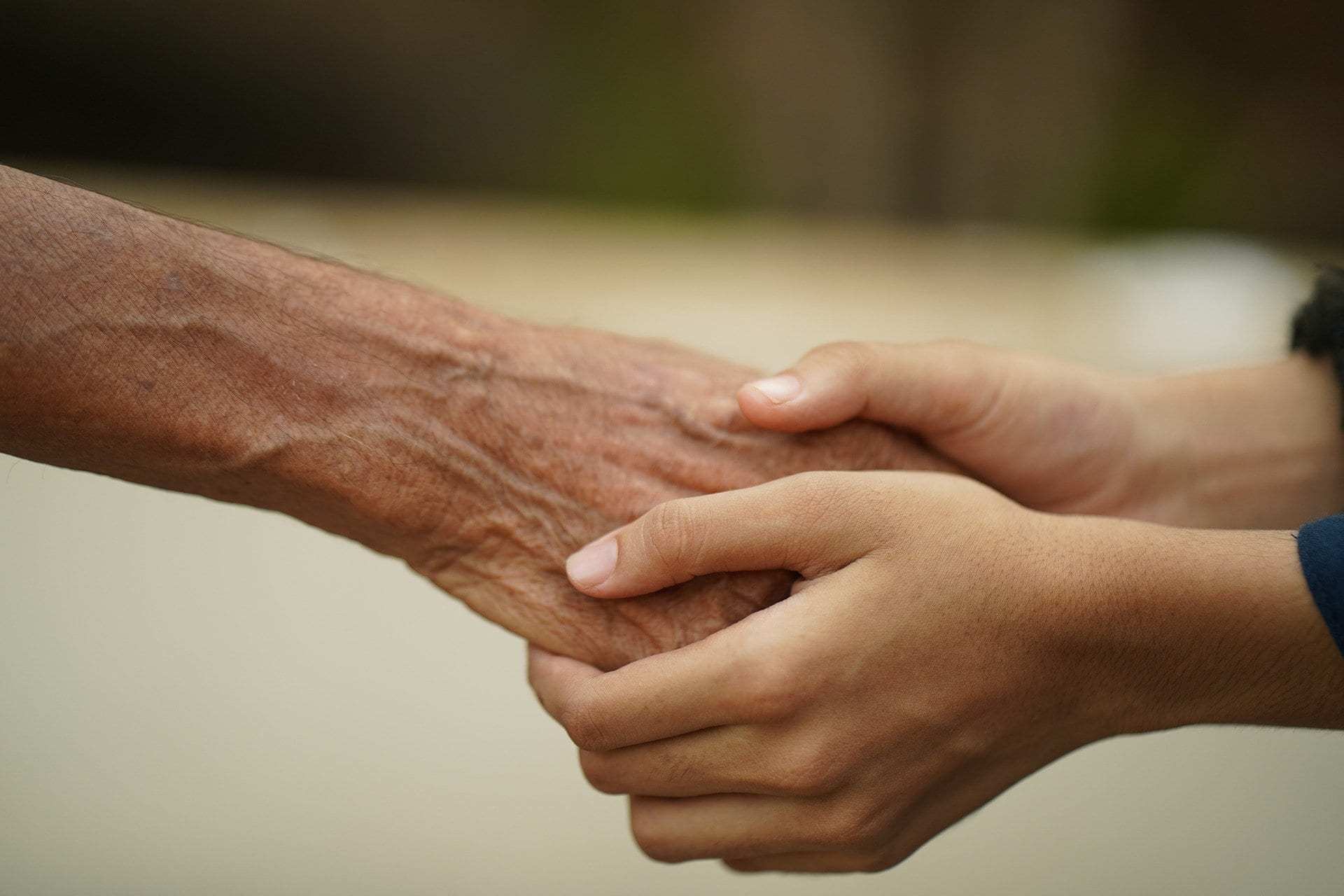 A young person's hands take those of an older person