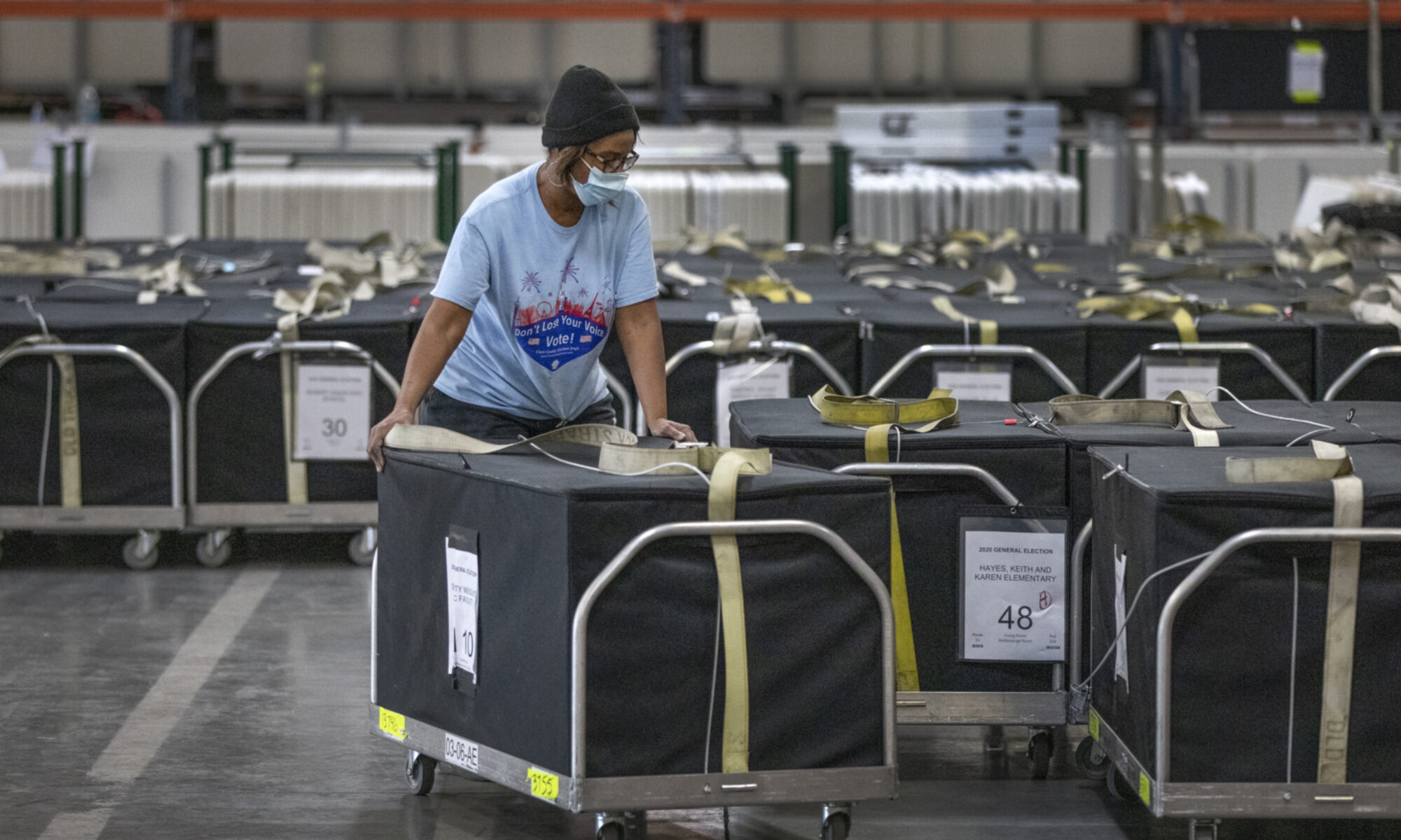 registrar of voter staffer wheels cart with ballots