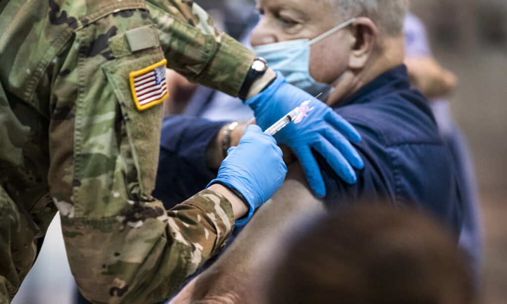 A National Guard member injects elderly man with COVID-19 vaccine