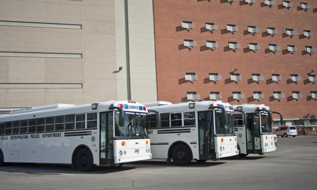 Three white buses parked outside a building