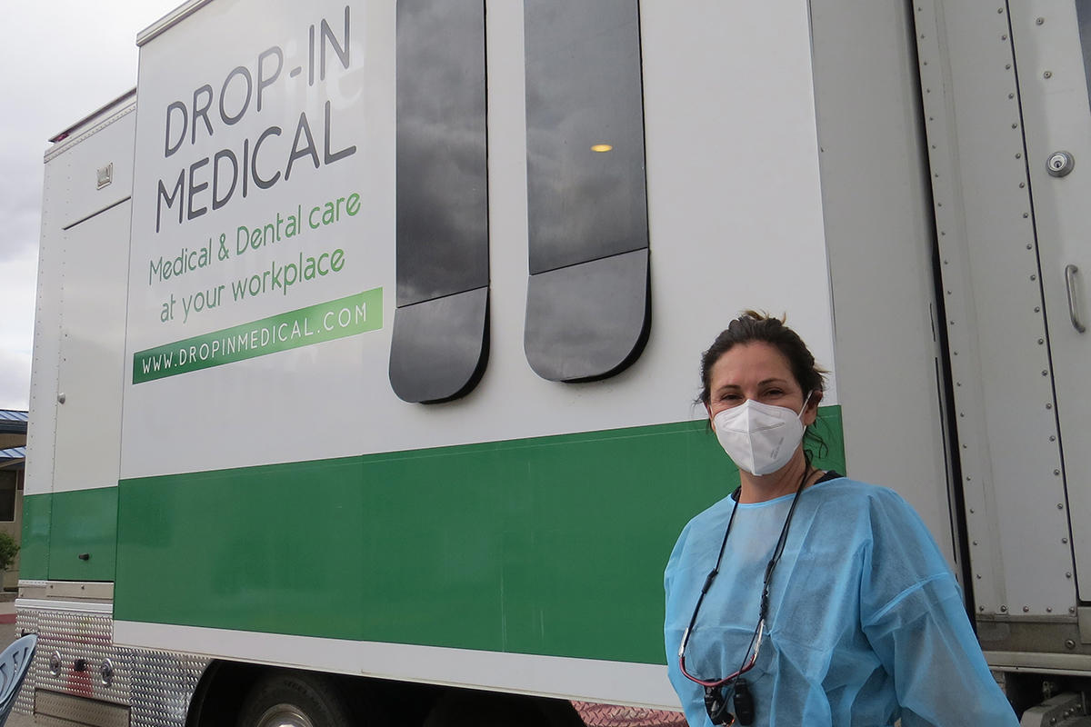 Woman stands outside in front of a van, wearing dental physician attire.