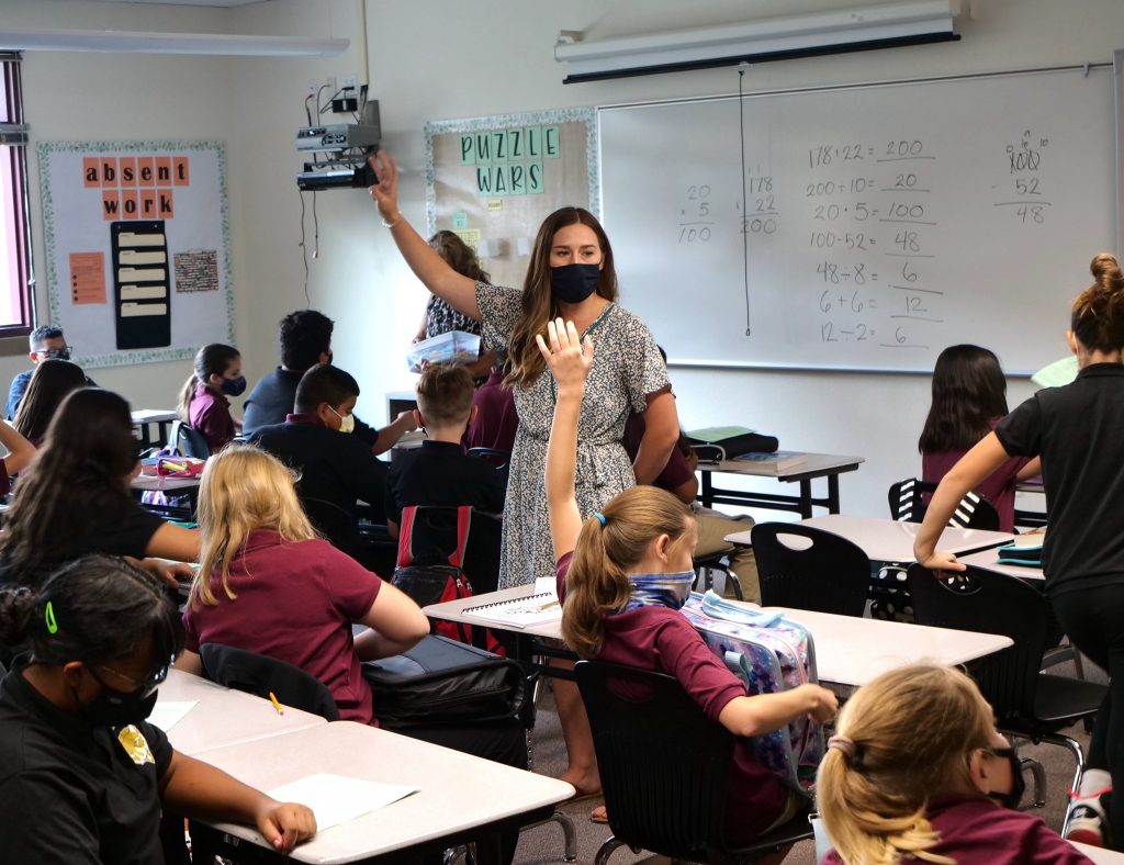 masked teacher with masked children in classroom