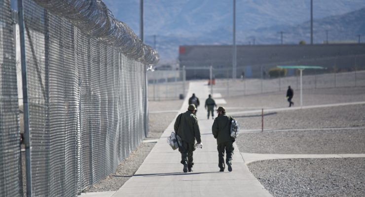Two individuals walk toward prison