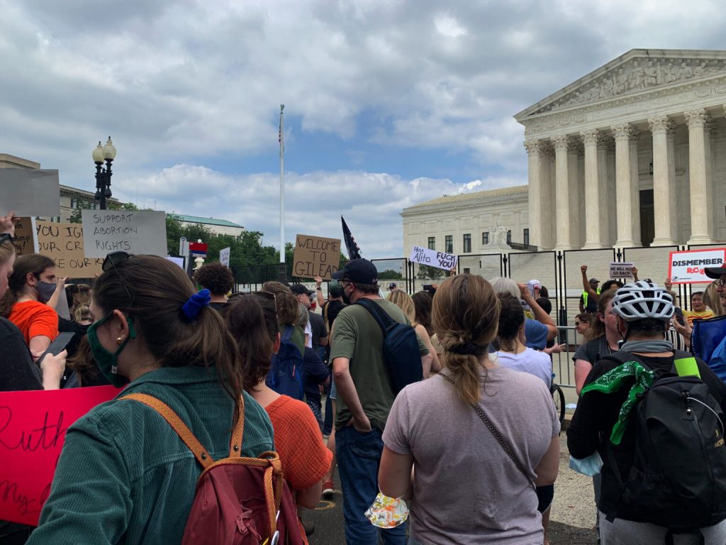 protestors hold signs in front of U.S. Supreme Court
