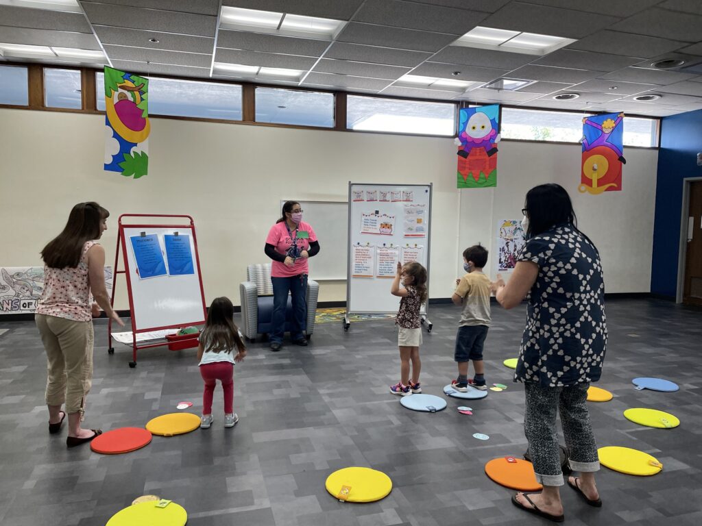 Children and adults stand and play in library