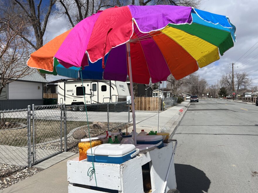 a white food cart with rainbow umbrella