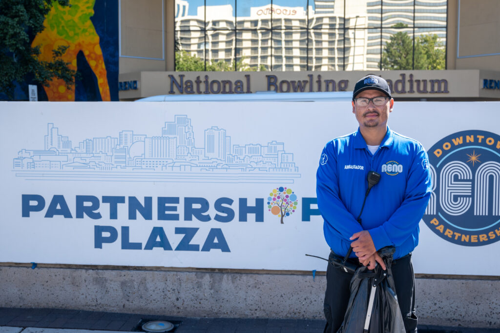 Man stands in front of "Partnership Plaza" sign.
