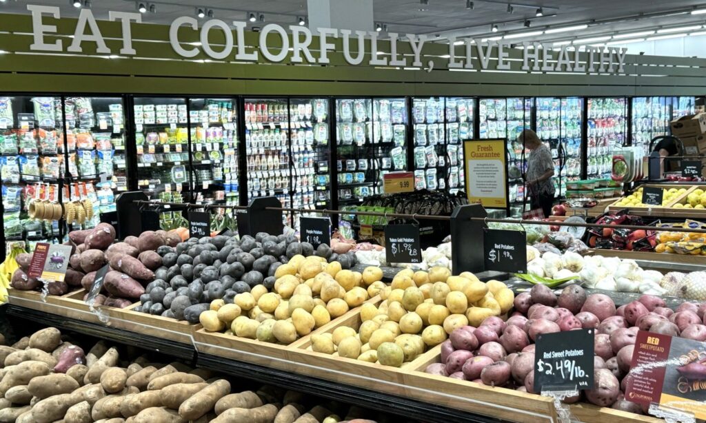 Una vista de fruta y verduras en una tienda. Palabras "Eat, Colorfully, Live Healthy"