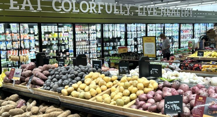 Una vista de fruta y verduras en una tienda. Palabras "Eat, Colorfully, Live Healthy"