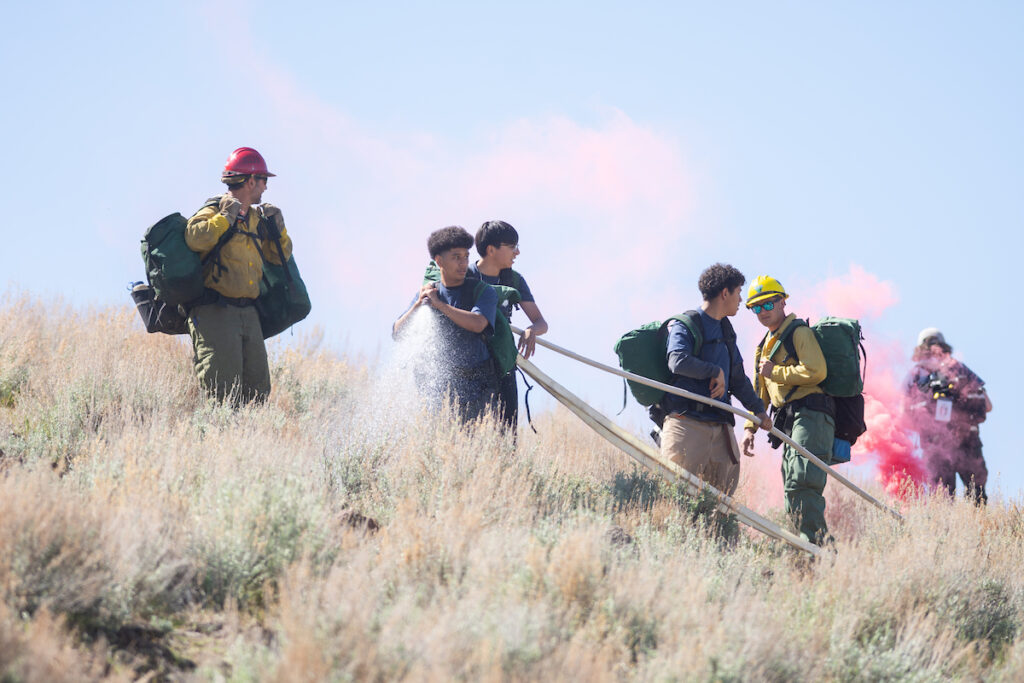 Students are pictured training for wildfires by handling a hose