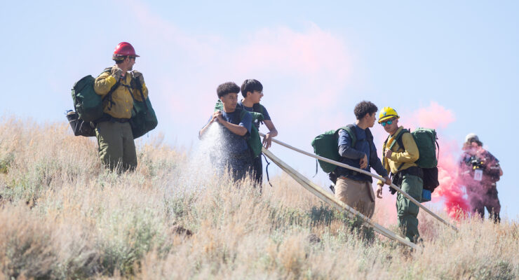 Students are pictured training for wildfires by handling a hose