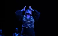 woman dances on stage with hands near her face