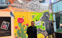 Man stands in building hallway in front of mural