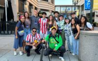 About a dozen people pose outside for a photo, some wear red and white jersey for the Paraguay soccer team.
