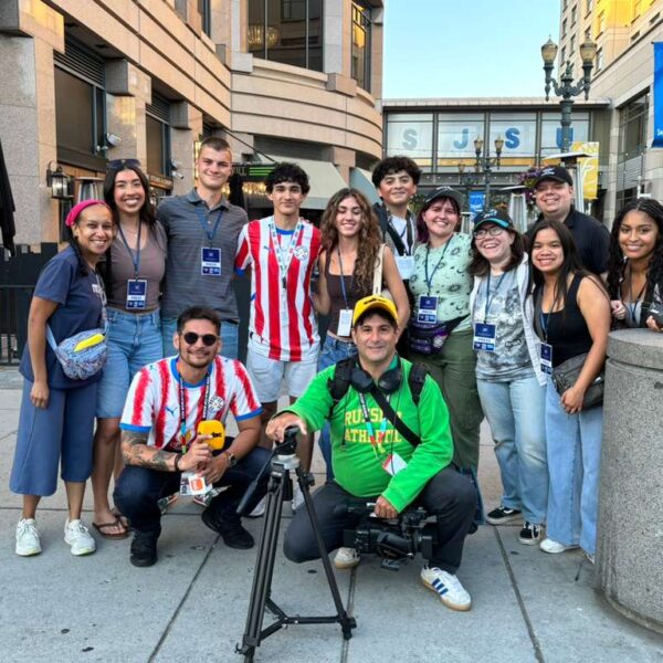 About a dozen people pose outside for a photo, some wear red and white jersey for the Paraguay soccer team.