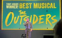 man on stage sings into microphone