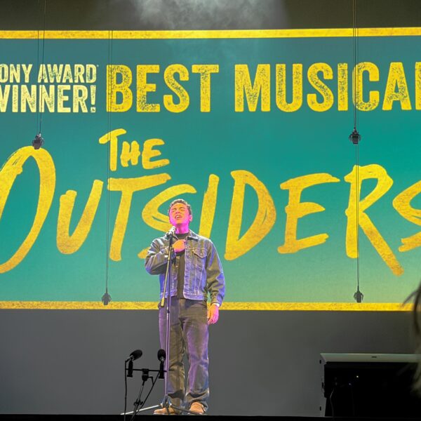 man on stage sings into microphone