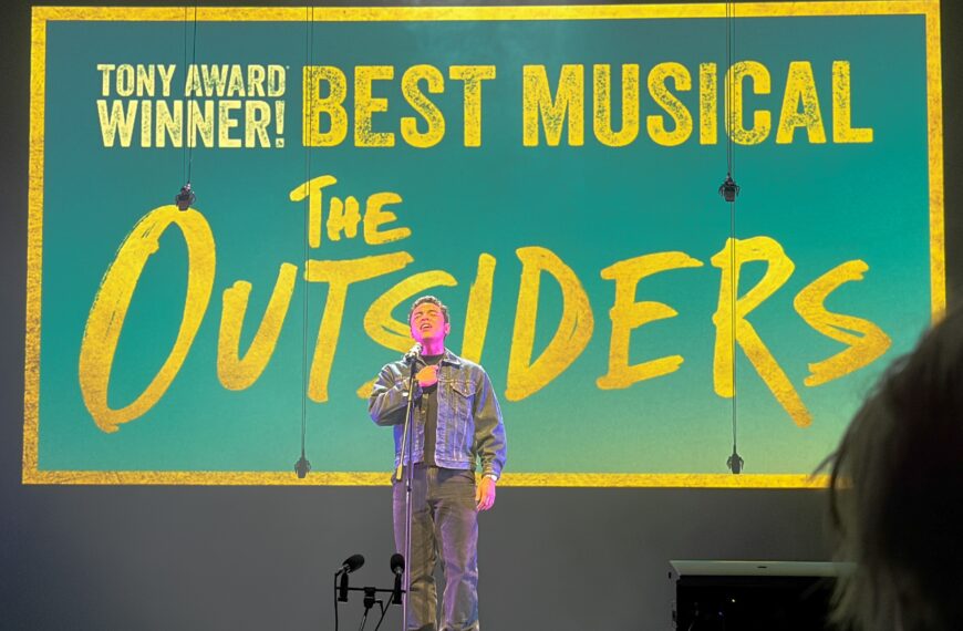 man on stage sings into microphone