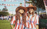 two women with hats and Paraguay soccer jersey smile at camera