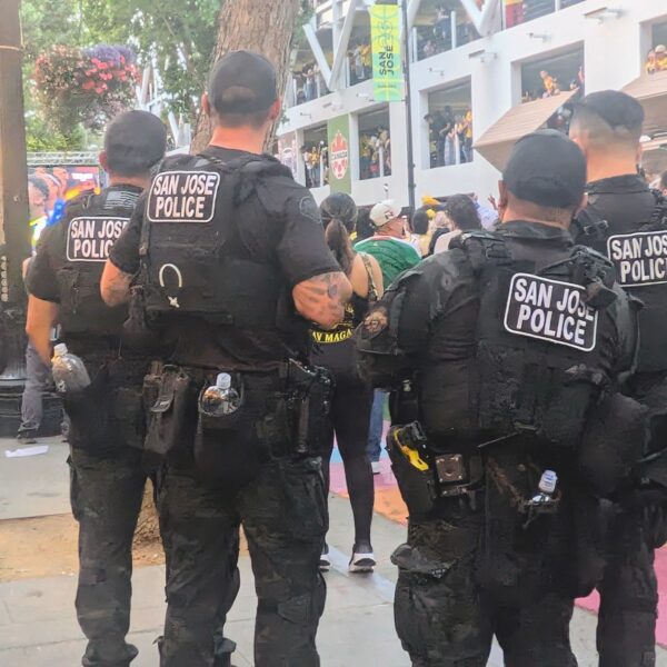 four san josé police officers look over a crowd