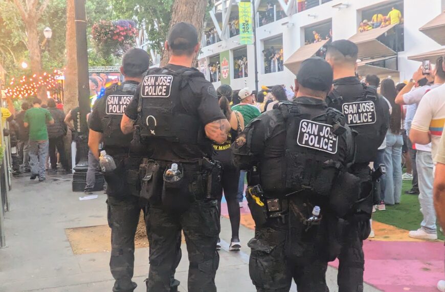 four san josé police officers look over a crowd